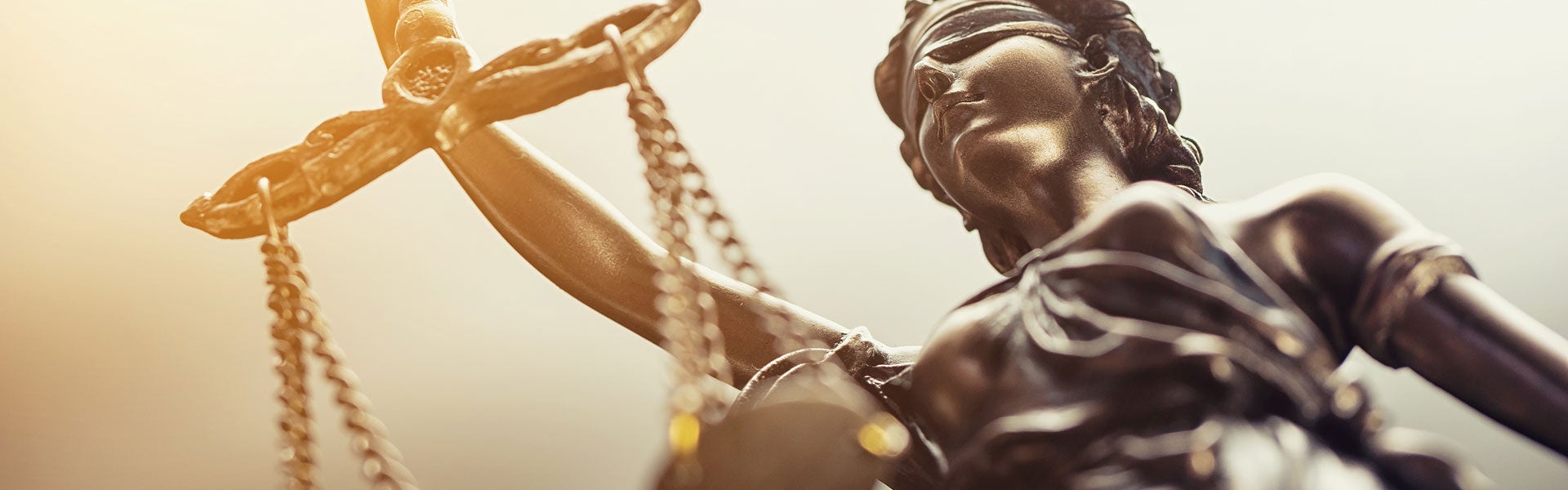 A low-angle, close-up shot of Lady Justice, a blindfolded figure holding scales.